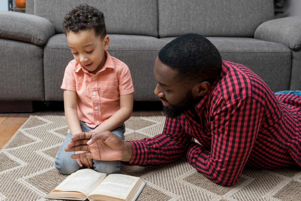 black father son reading book floor sm