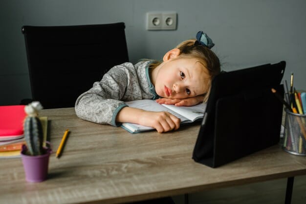 tired sleepy little girl having online lesson home
