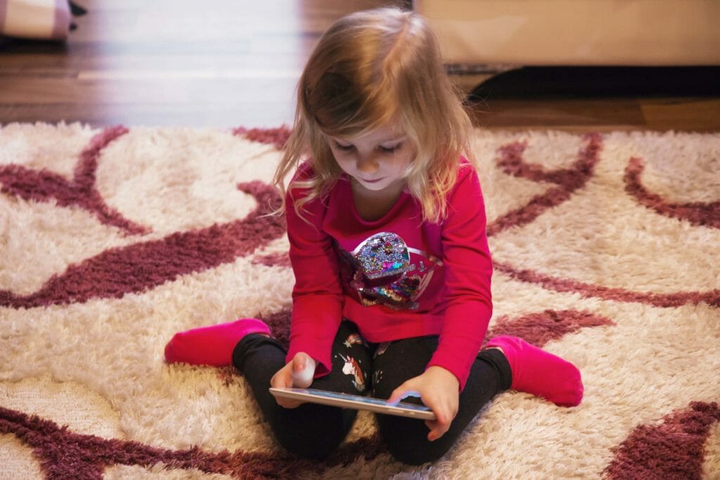 girl playing tablet game floor
